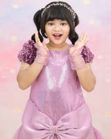 Shimmery Pink Dress With Satin Flower Sleeves Adorned With Pearl Tassels And A Large Bow Accent.