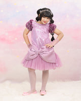 Shimmery Pink Dress With Satin Flower Sleeves Adorned With Pearl Tassels And A Large Bow Accent.