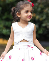 White Crop Top Paired With A Flared Skirt Featuring Vibrant Pink Floral Embroidery Along The Hem