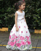 White Crop Top Paired With A Flared Skirt Featuring Vibrant Pink Floral Embroidery Along The Hem