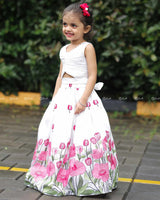 White Crop Top Paired With A Flared Skirt Featuring Vibrant Pink Floral Embroidery Along The Hem