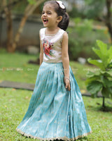 Sleeveless Pink Top With Floral Print And Pearls, Paired With Pleated Blue Brocade Skirt And Golden Lace Hem