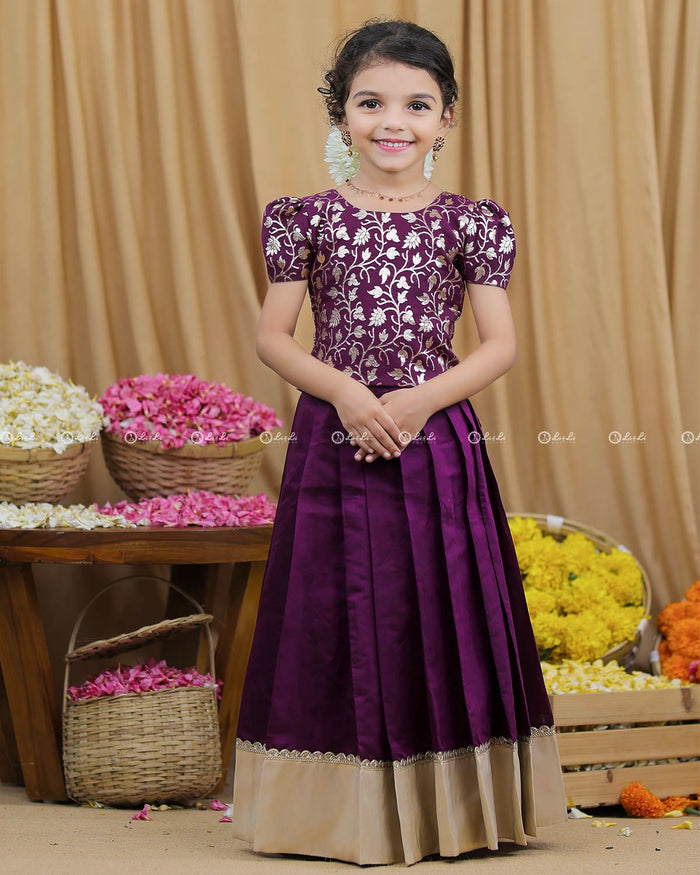 Girl in plum purple brocade puff sleeve top and pleated skirt with beige border