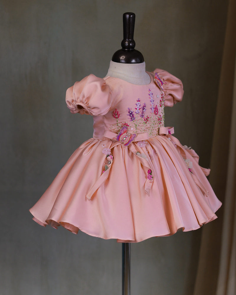 Butterfly and Floral Theme Peach Frock with Attached Bows in waistline and Applique Works.