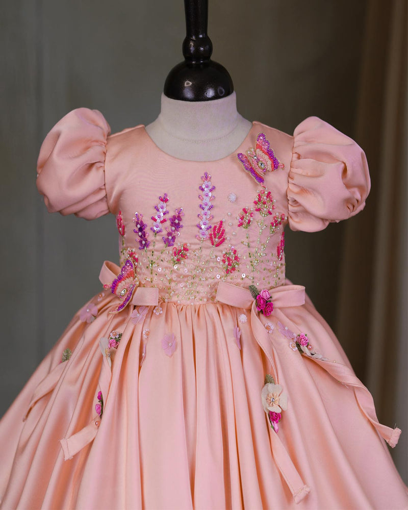 Butterfly and Floral Theme Peach Frock with Attached Bows in waistline and Applique Works.