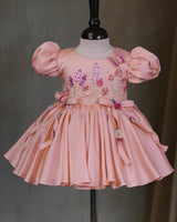 Butterfly and Floral Theme Peach Frock with Attached Bows in waistline and Applique Works.
