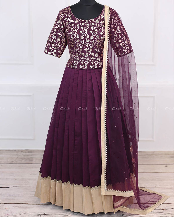 Woman in plum purple brocade top, pleated skirt and net dupatta