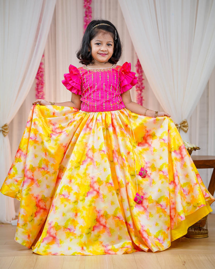 Girl in fuchsia ruffle sleeve top and yellow pink shibori print umbrella skirt